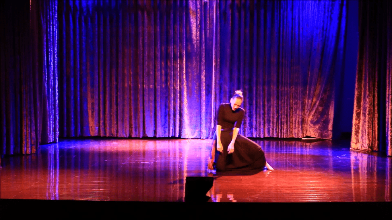 gillian performing on a colorful stage wearing black and in the process of falling
