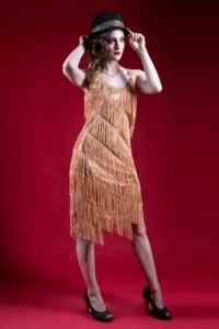 Gillian as a woman in a flapper dress holding a fedora