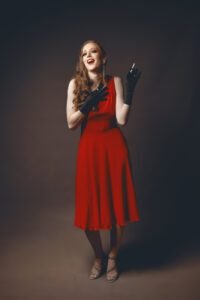 A glamorous lady in red laughing while holding a cigarette