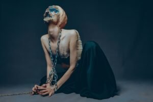 a beautiful but alien creature chained at the neck and wrists