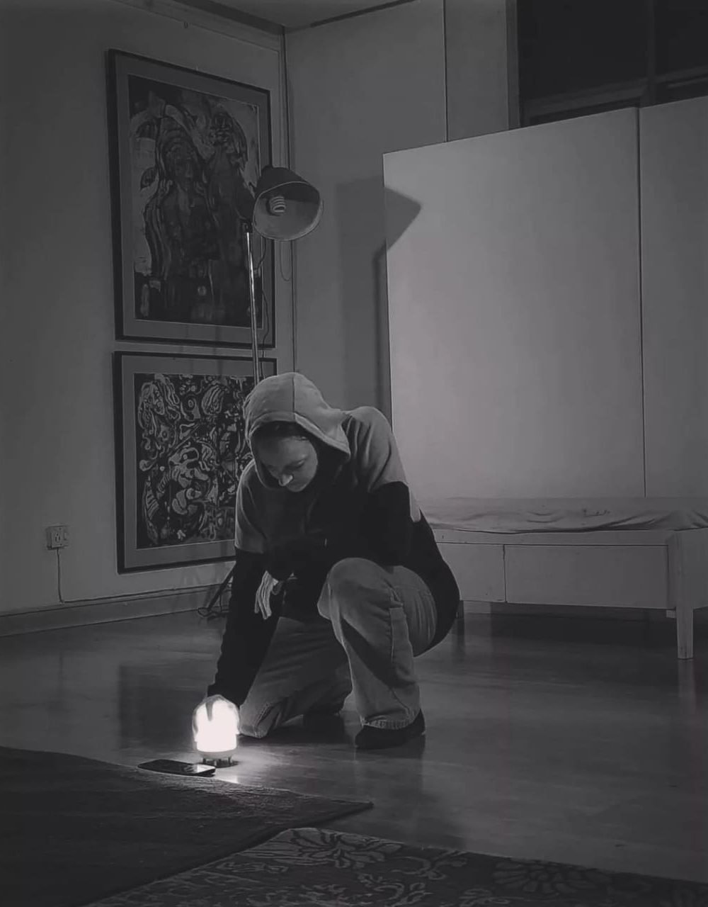 Gillian in a hoodie kneeling with a small lamp